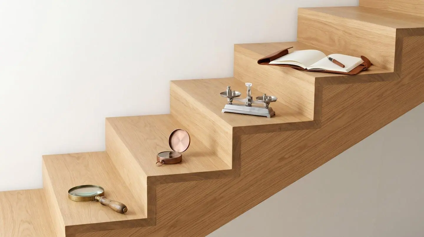 Escalier en bois clair montant en diagonale avec quatre marches, chacune portant un objet symbolique : loupe, boussole, balance et carnet ouvert avec stylo